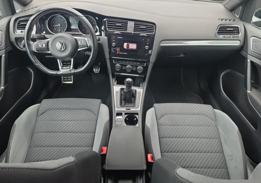 Vue intérieure avant de la Volkswagen Golf 1.5 TSI EVO 150 R-line noire de 2019 avec volant multifonction et boîte manuelle.