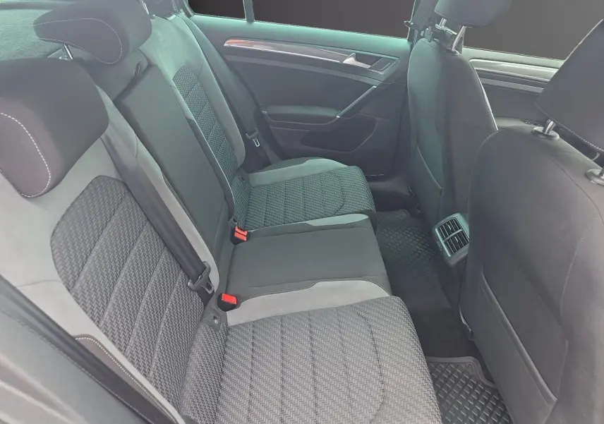 Vue intérieure côté arrière droit montrant les sièges arrière en tissu gris avec surpiqûres blanches d’une Volkswagen Golf 1.5 TSI EVO 2019.