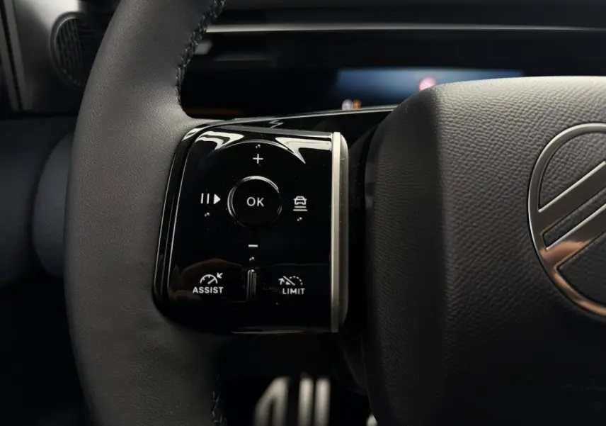 Gros plan sur les commandes noires brillantes au volant cuir noir du Citroën C5 Aircross hybride 2026.