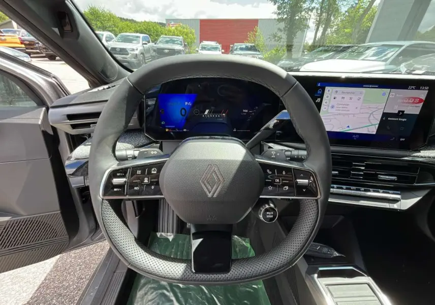 Vue intérieure centrée sur le volant multifonctions et l'écran tactile de la Renault Clio gris schiste 2026.