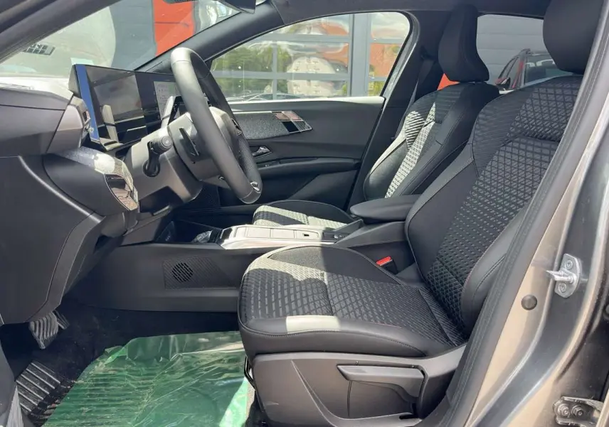 Vue intérieure côté conducteur de la Renault Clio gris schiste 2026, sièges tissu à motifs et tableau de bord moderne.