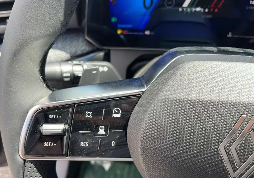 Gros plan sur le volant multifonctions noir de la Renault Clio 6 TCE 115 EDC Techno avec commandes de régulateur.