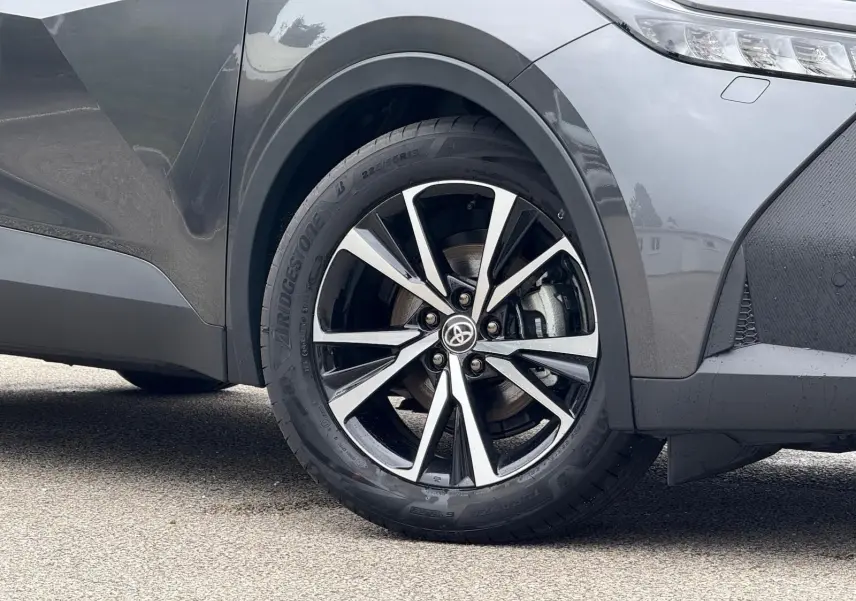 Gros plan sur la roue avant droite du Toyota C-HR gris atlas 2025, mettant en valeur la jante alliage noire et argent.