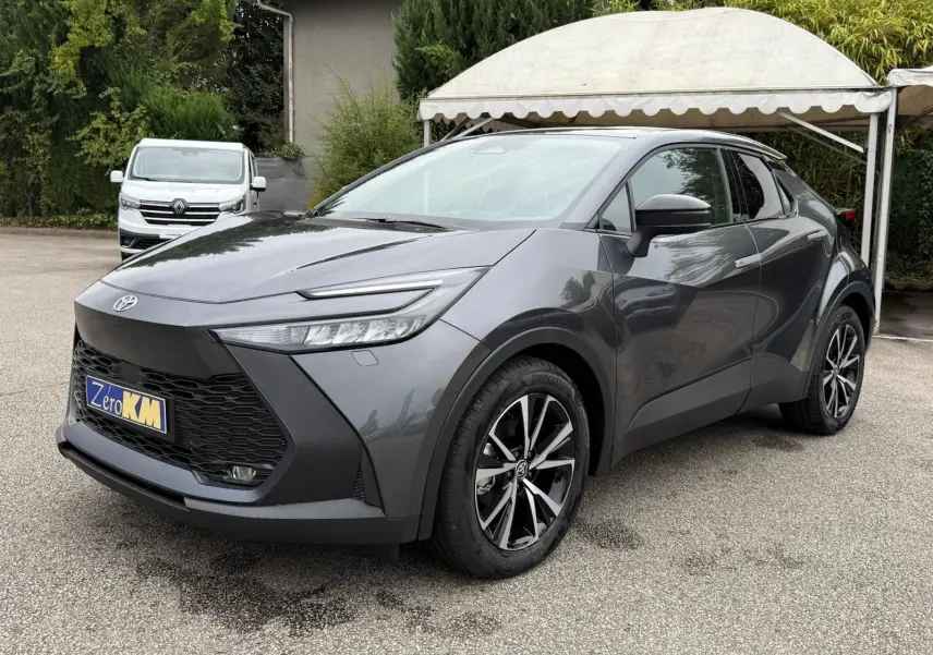 Toyota C-HR 1.8 140CH STYLE gris atlas vu en 3/4 avant droit avec jantes noires et détails noirs contrastants.