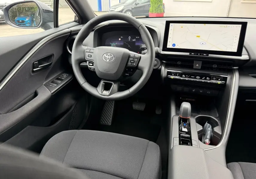 Vue intérieure avant du Toyota C-HR 1.8 140CH STYLE MY25 avec tableau de bord numérique et écran tactile central.