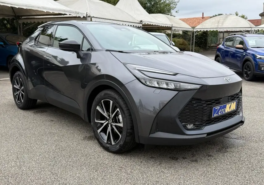 Toyota C-HR 1.8 140CH STYLE gris atlas en 3/4 avant droit, avec jantes alliage et calandre noire distinctive.