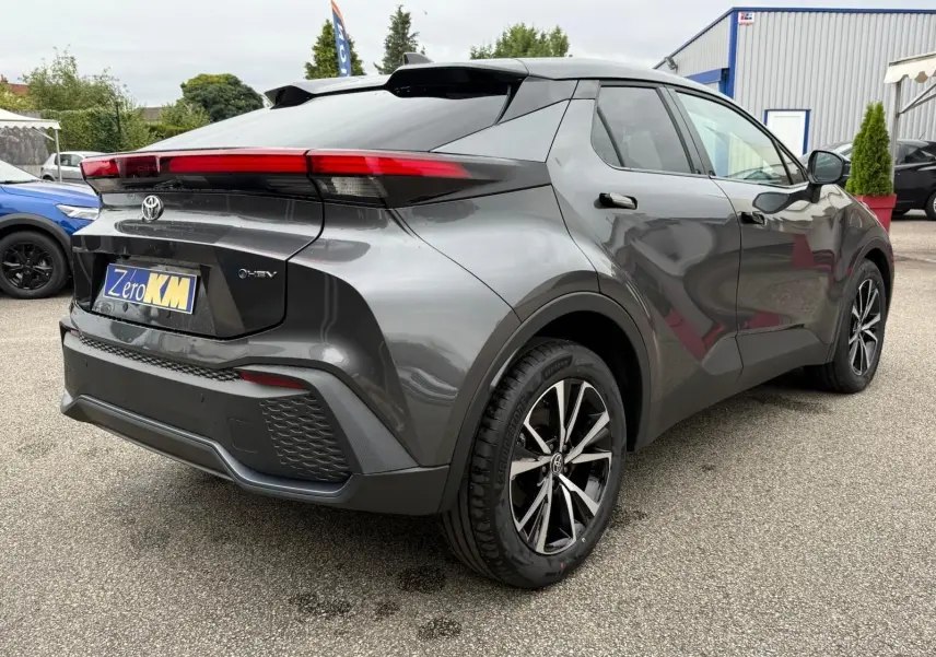 Vue 3/4 arrière droite du Toyota C-HR 1.8 140CH STYLE gris atlas avec feux arrière étirés et jantes noires bicolores.
