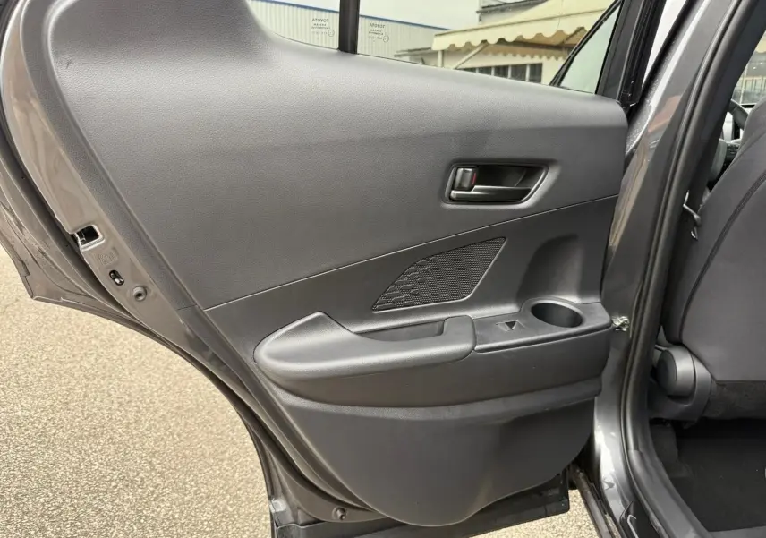 Vue intérieure de la porte arrière gauche gris atlas du Toyota C-HR 1.8 140CH STYLE MY25 avec accoudoir et porte-gobelet intégré.