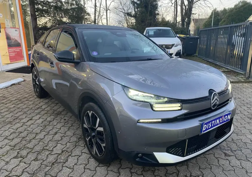 Citroën C4 gris foncé vue 3/4 avant droit avec toit noir et feux LED allumés sur parking extérieur.