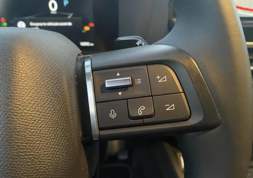Gros plan sur les commandes multifonctions à gauche du volant de la Citroën C4 2025 gris foncé.