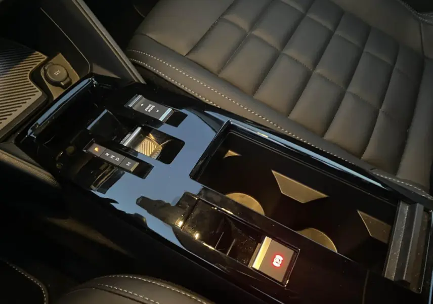 Vue rapprochée de la console centrale noire brillante avec levier de boîte auto et siège en cuir gris foncé du Citroën C4 2025.