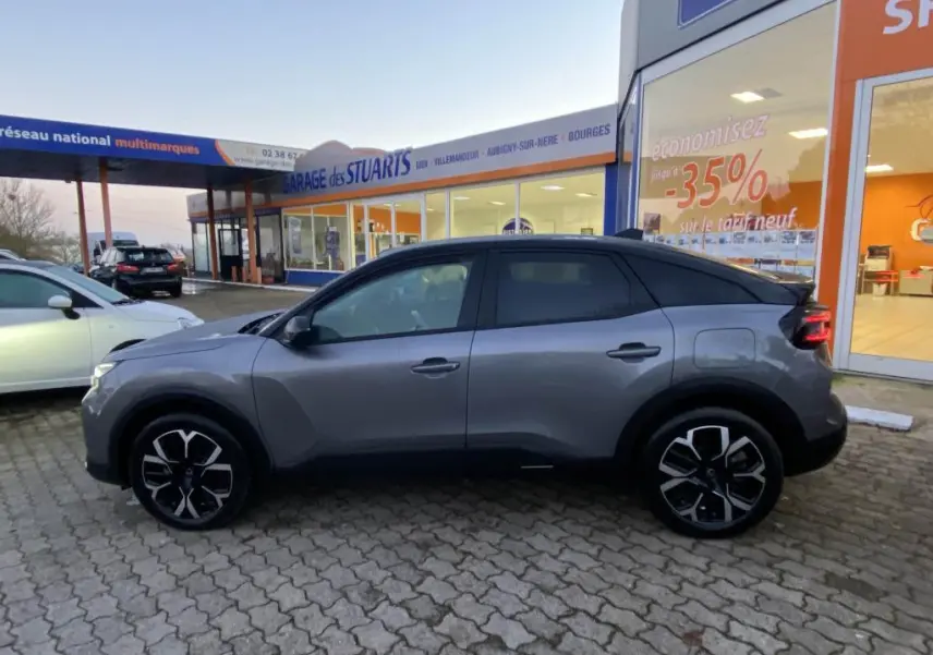 Profil droit d'une Citroën C4 2025 gris foncé avec toit bi-ton noir, jantes stylisées et vitres teintées.