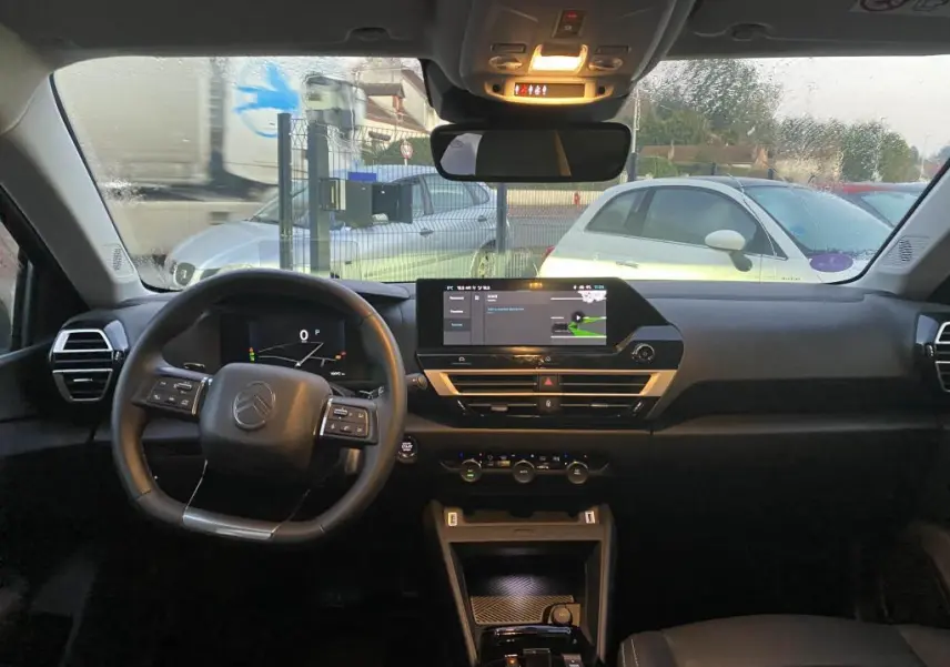 Vue intérieure avant de la Citroën C4 gris foncé 2025, avec tableau de bord digital et écran tactile central allumé.