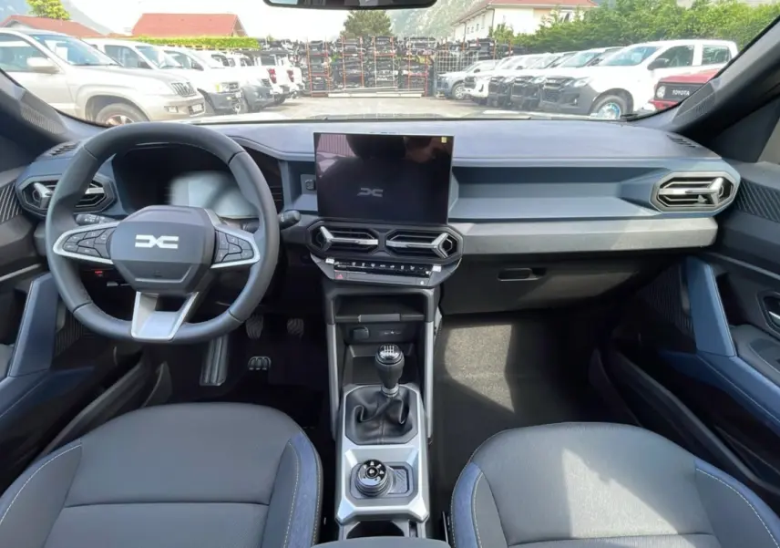 Vue intérieure avant du Dacia Bigster noir perle, mettant en valeur le volant cuir, la console centrale et l'écran tactile.