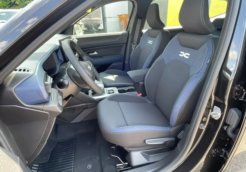Vue intérieure côté conducteur du Dacia Bigster noir perle, sièges tissu noir et bleu avec logo DC brodé.