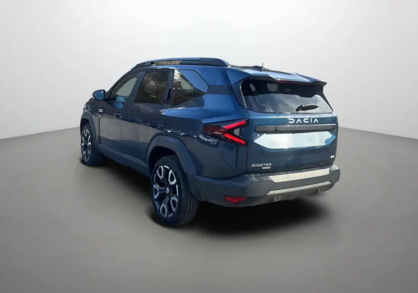 Vue 3/4 arrière droite du Dacia Bigster bleu indigo avec jantes alu 19 pouces et hayon électrique dans un studio.