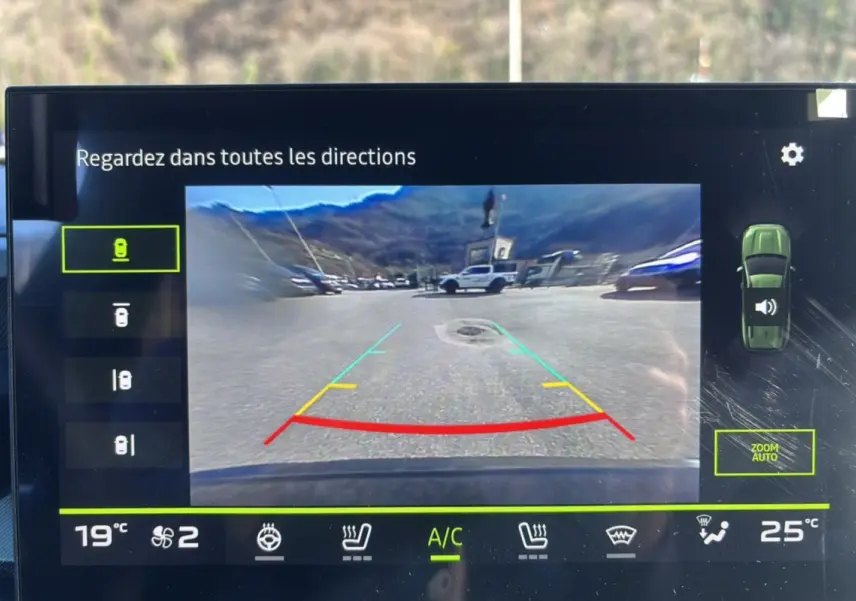 Écran multimédia montrant la caméra multiview arrière du Dacia Bigster bleu indigo avec lignes de guidage colorées.