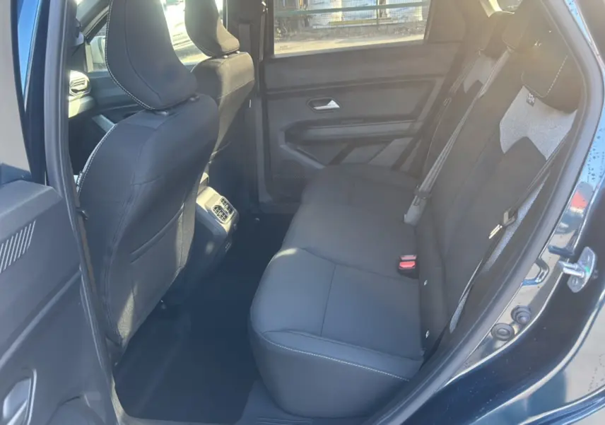 Vue intérieure arrière côté gauche du Dacia Bigster 2026 bleu indigo, montrant la banquette noire et les détails des sièges.