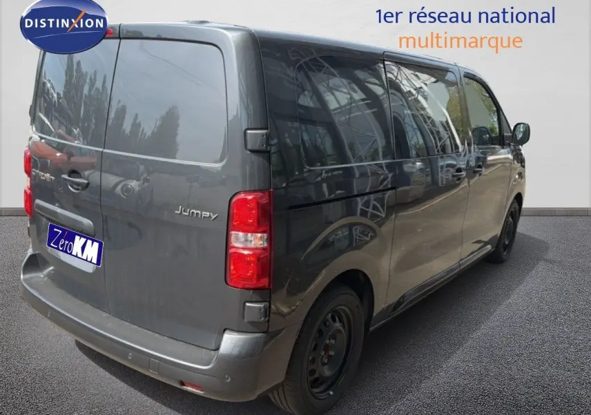 Vue 3/4 arrière droit d'un Citroën Jumpy cabine approfondie gris titane métallisé avec vitres teintées et feux arrière rouges.