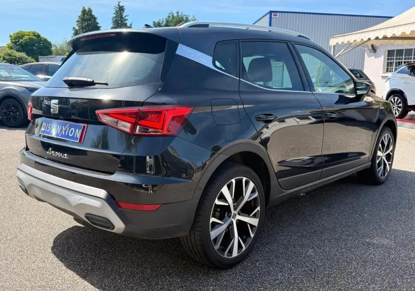 Vue 3/4 arrière droite d'une SEAT Arona noire avec jantes alliage et toit contrasté gris clair.