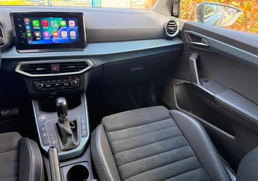 Vue intérieure côté passager du tableau de bord et console centrale noire du SEAT Arona 2022 avec écran tactile et sellerie mixte.