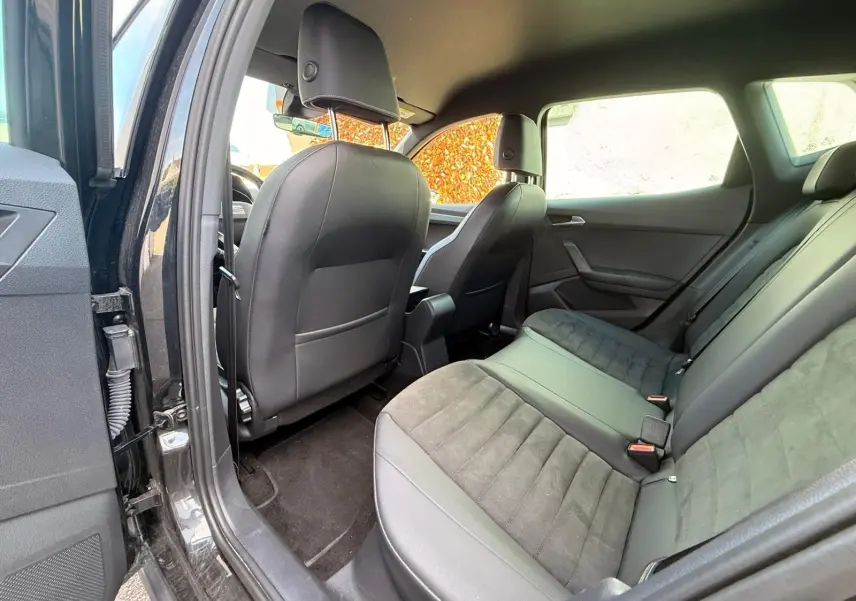 Vue intérieure arrière côté gauche du SEAT Arona 2022 avec sièges mixtes tissu et cuir noir.
