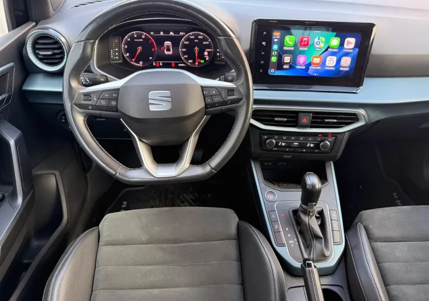 Vue intérieure du poste de conduite du SEAT Arona 2022, volant cuir noir, écran tactile central affichant Apple CarPlay.