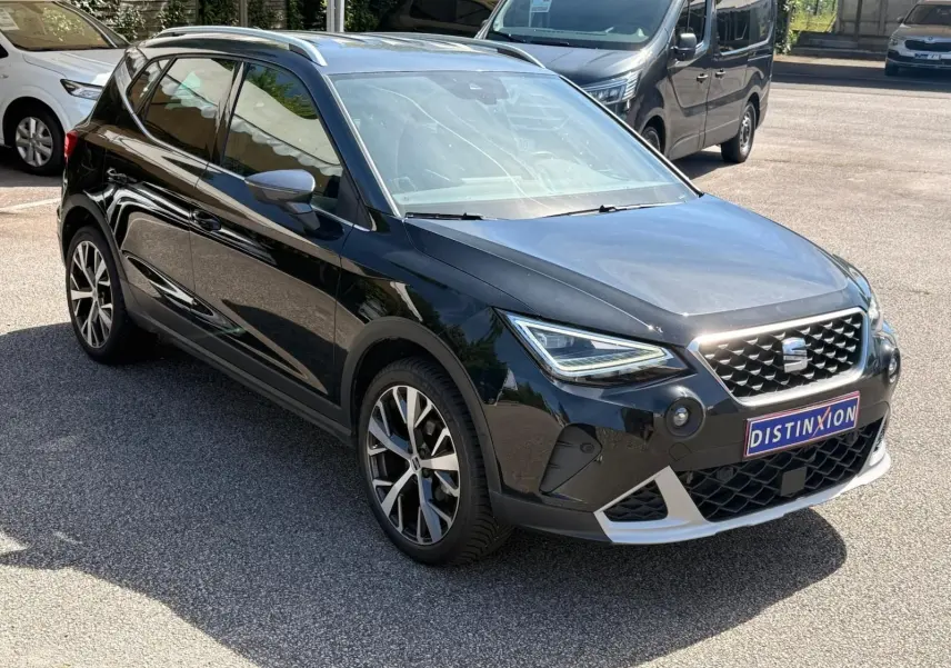 Vue 3/4 avant droite d'une SEAT Arona noire avec jantes alliage et calandre distinctive, stationnée en extérieur.