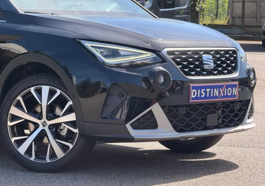 Vue 3/4 avant droite d'un SEAT Arona noir avec calandre chromée et jantes alliage distinctives.
