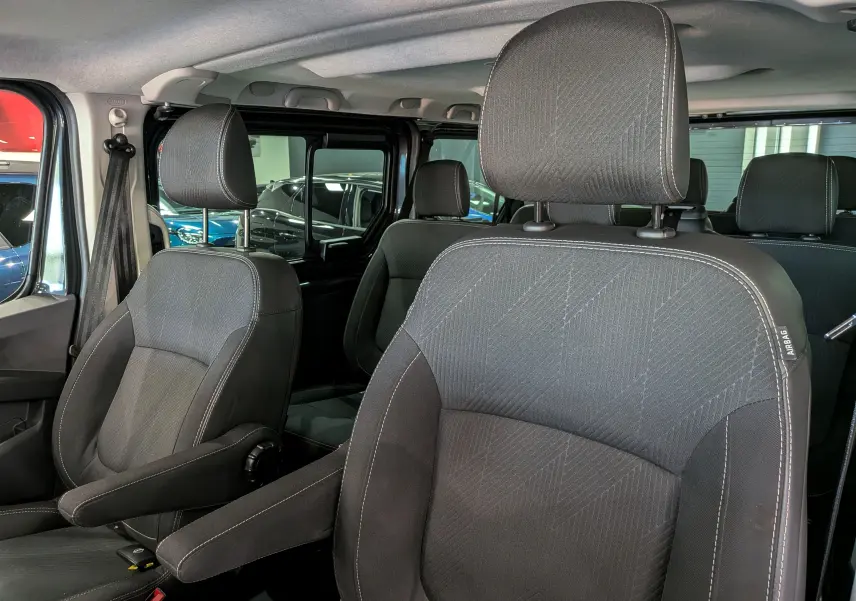 Vue intérieure rapprochée des sièges avant en tissu gris foncé du Nissan Primastar Combi L1H1 2025.