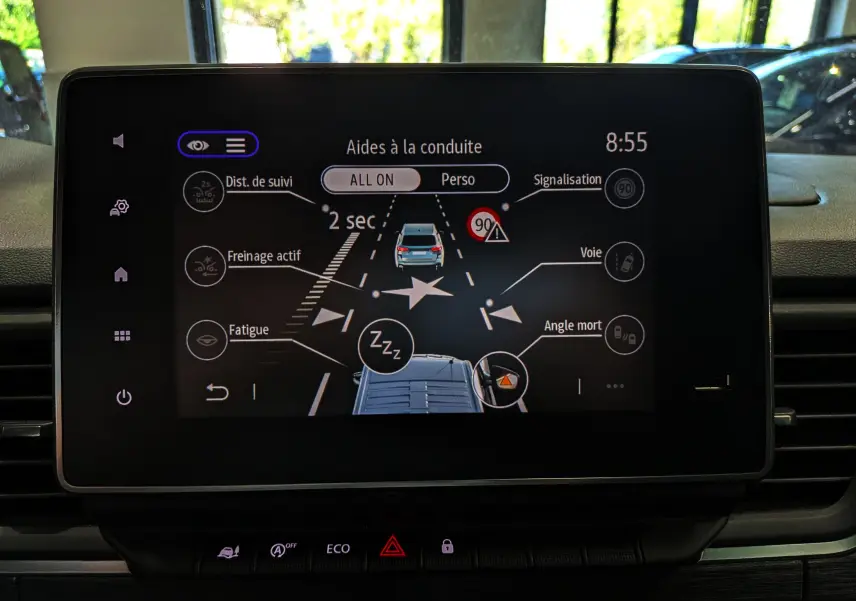 Écran central affichant les aides à la conduite du Nissan Primastar Combi gris Comète, vue intérieure frontale.