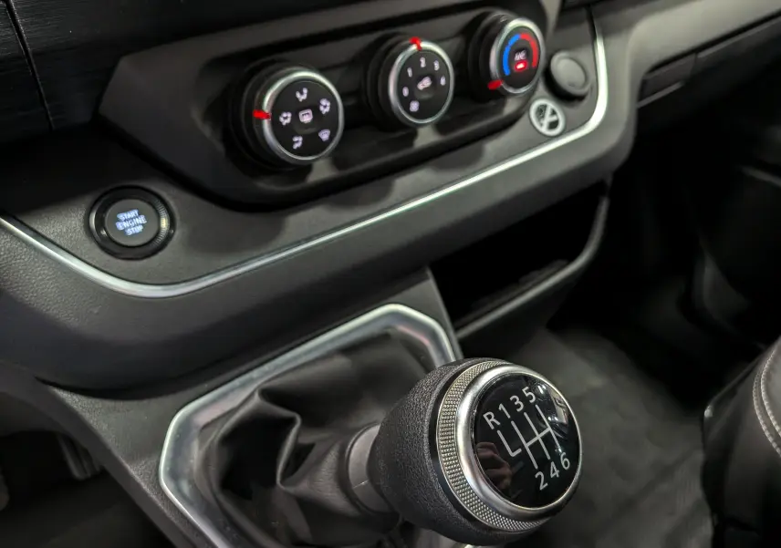 Gros plan sur la commande de boîte manuelle et les réglages de climatisation du Nissan Primastar Combi gris Comète 2025.