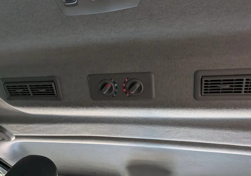Vue intérieure du plafond du Nissan Primastar Combi gris, montrant les commandes de ventilation arrière et deux bouches d'aération.