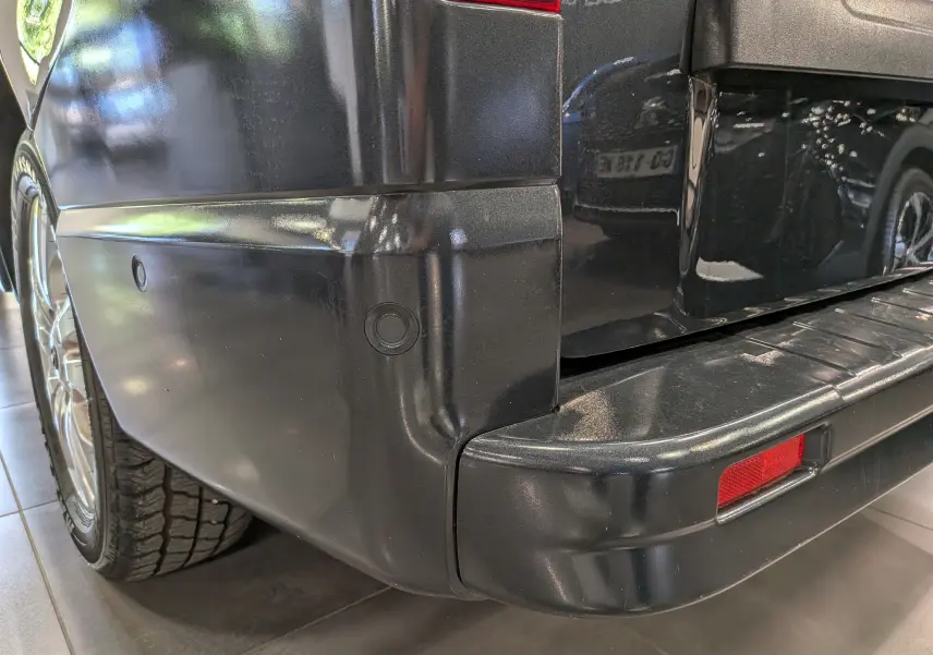 Gros plan sur l’angle arrière gauche du Nissan Primastar Combi gris Comète, mettant en valeur le pare-chocs et le feu arrière.