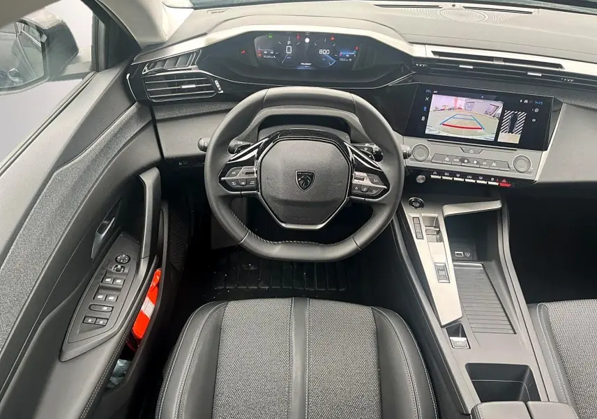 Vue intérieure avant centrée sur le volant noir multifonction et l’écran tactile affichant la caméra de recul de la Peugeot 308.