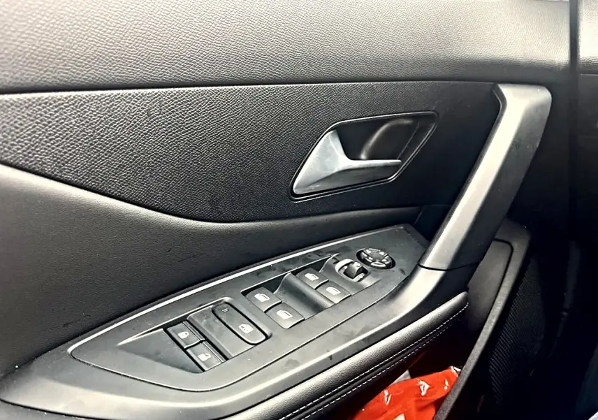 Gros plan sur la porte côté conducteur noire de la Peugeot 308 2025 avec commandes des vitres et poignée argentée.