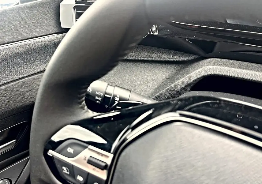 Vue rapprochée du volant noir multifonction et du tableau de bord intérieur gris de la Peugeot 308 2025.