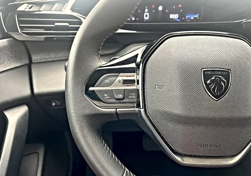 Vue rapprochée du volant noir de la Peugeot 308 2025 avec commandes multifonctions et logo lion central.