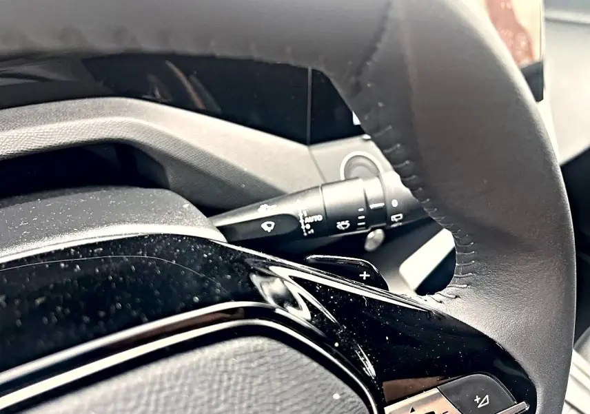 Gros plan sur le volant noir de la Peugeot 308 2025 avec commandes intégrées et palettes au volant.