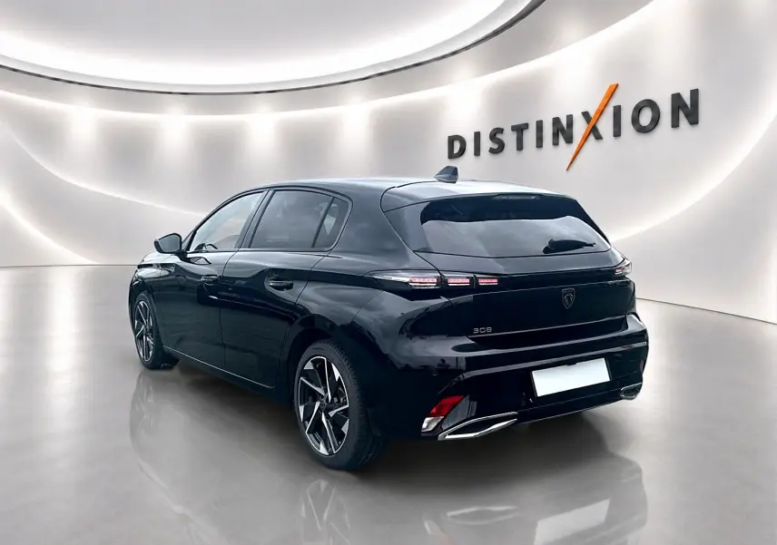 Peugeot 308 noire vue 3/4 arrière droit, jantes alu distinctives et feux arrière LED dans un showroom lumineux.