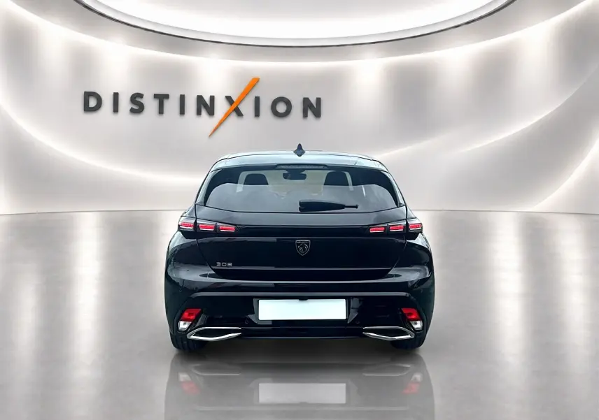 Vue arrière d'une Peugeot 308 noire 2025 avec feux LED et double sortie d'échappement chromée dans un showroom.