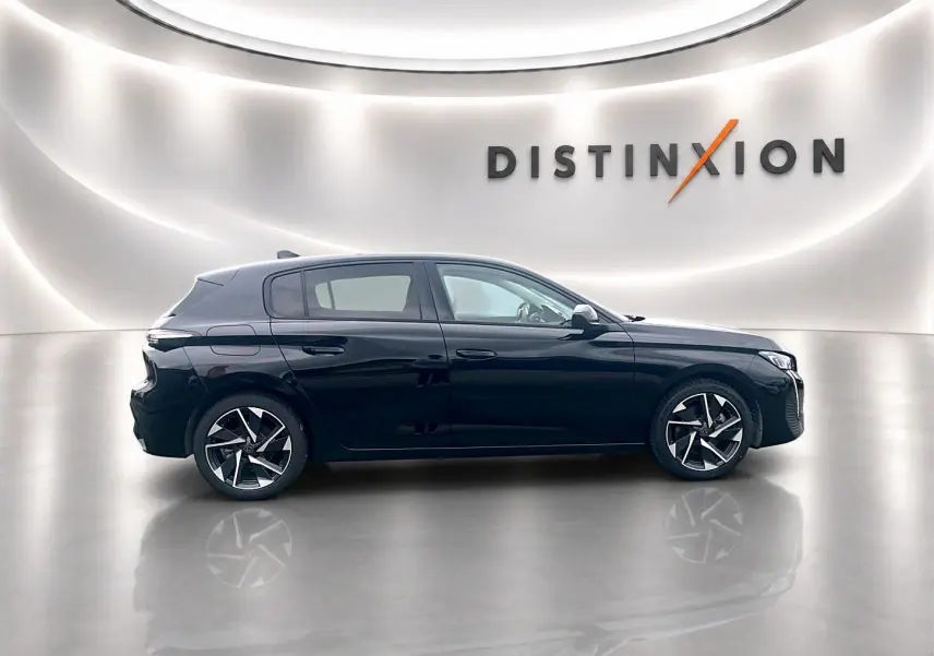 Profil côté gauche d'une Peugeot 308 noire 2025 avec jantes alu stylisées, dans un showroom lumineux "Distinxion".