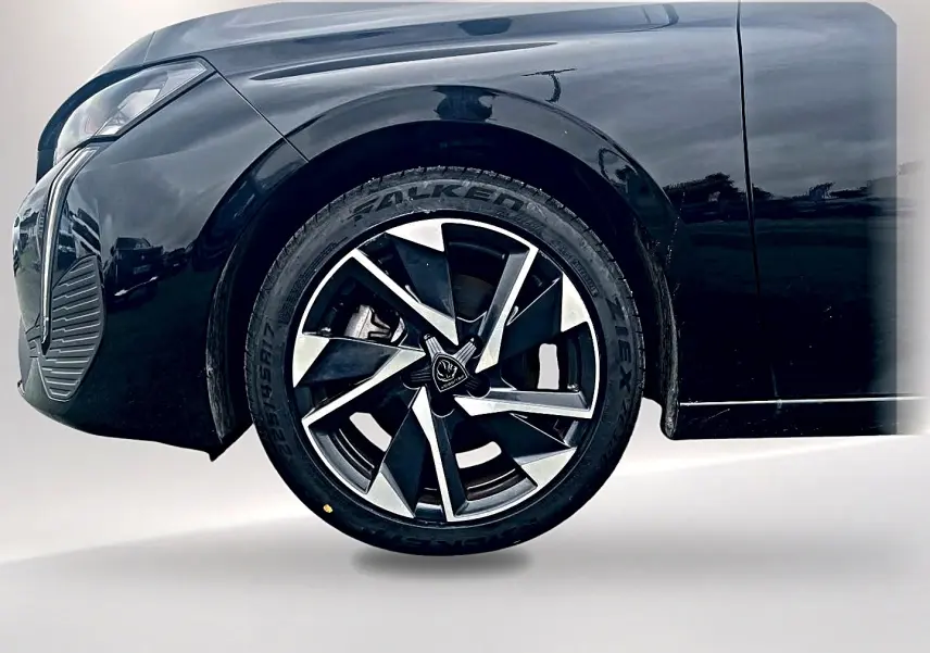 Gros plan sur la roue avant gauche d'une Peugeot 308 noire 2025 avec jante alliage au design moderne.