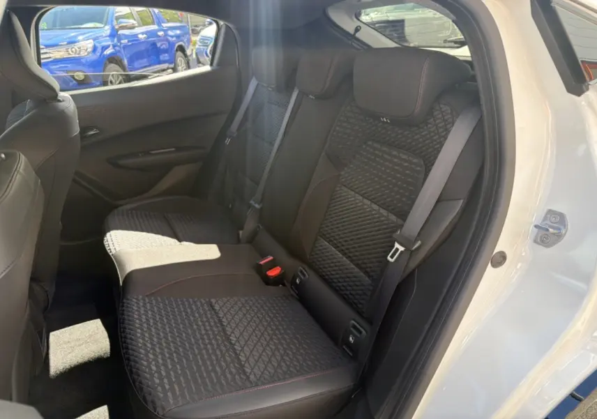 Vue intérieure côté droit sur la banquette arrière noire avec surpiqûres rouges d'une Renault Clio blanc glacier 2026.