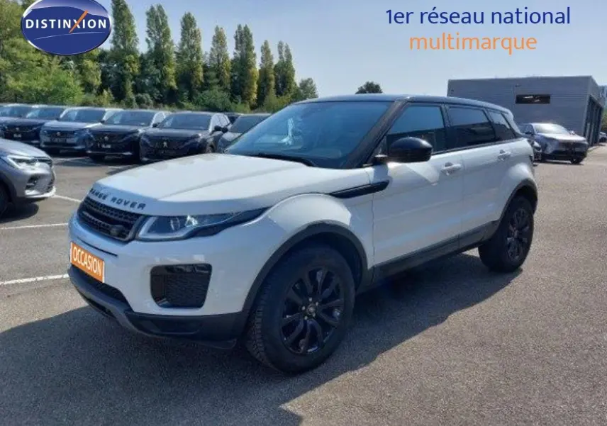 Vue 3/4 avant d'un Range Rover Evoque blanc 2018 avec détails noirs, garé sur un parking extérieur multimarque.