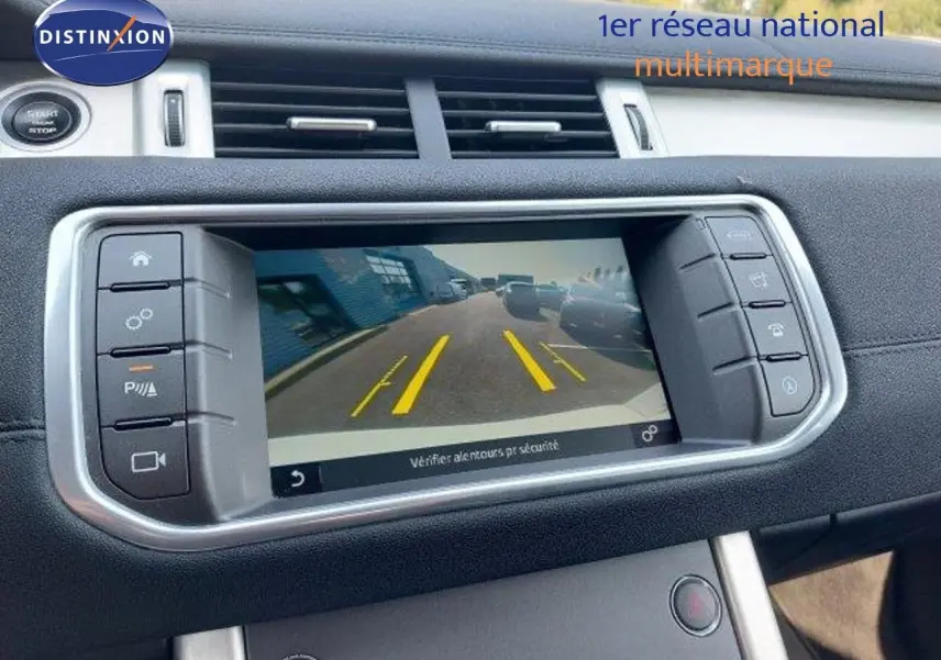 Écran central du tableau de bord du Range Rover Evoque blanc 2018 montrant la caméra de recul avec lignes de guidage jaunes.