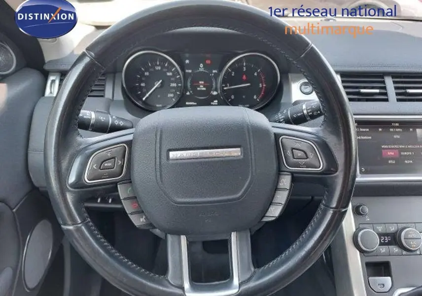 Vue rapprochée du volant noir du Range Rover Evoque blanc 2018 avec tableau de bord et commandes intégrées visibles.