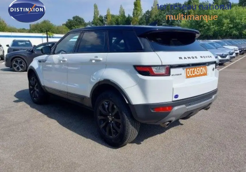 Vue 3/4 arrière droite d'un Range Rover Evoque blanc 2018 avec jantes noires et toit noir contrasté.
