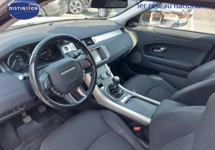 Intérieur noir du Range Rover Evoque 2018 vu côté conducteur, avec tableau de bord et boîte manuelle visibles.