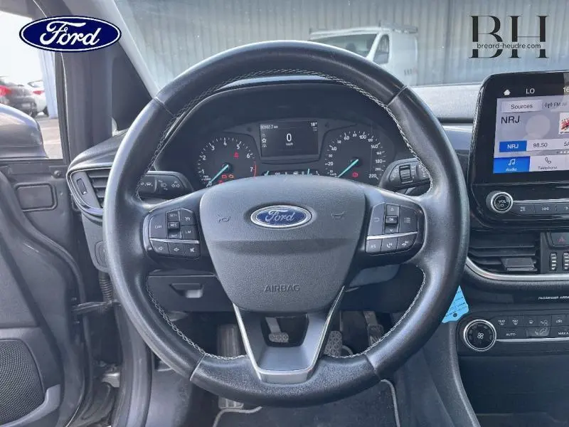 Vue intérieure centrée sur le volant cuir de la Ford Fiesta 2021, avec tableau de bord et écran tactile visibles.